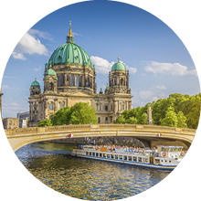Beautiful view of historic Berlin Cathedral (Berliner Dom) at famous Museum Island with ship passing Friedrichsbrucke bridge on Spree river in golden evening light at sunset in summer, Berlin, Germany