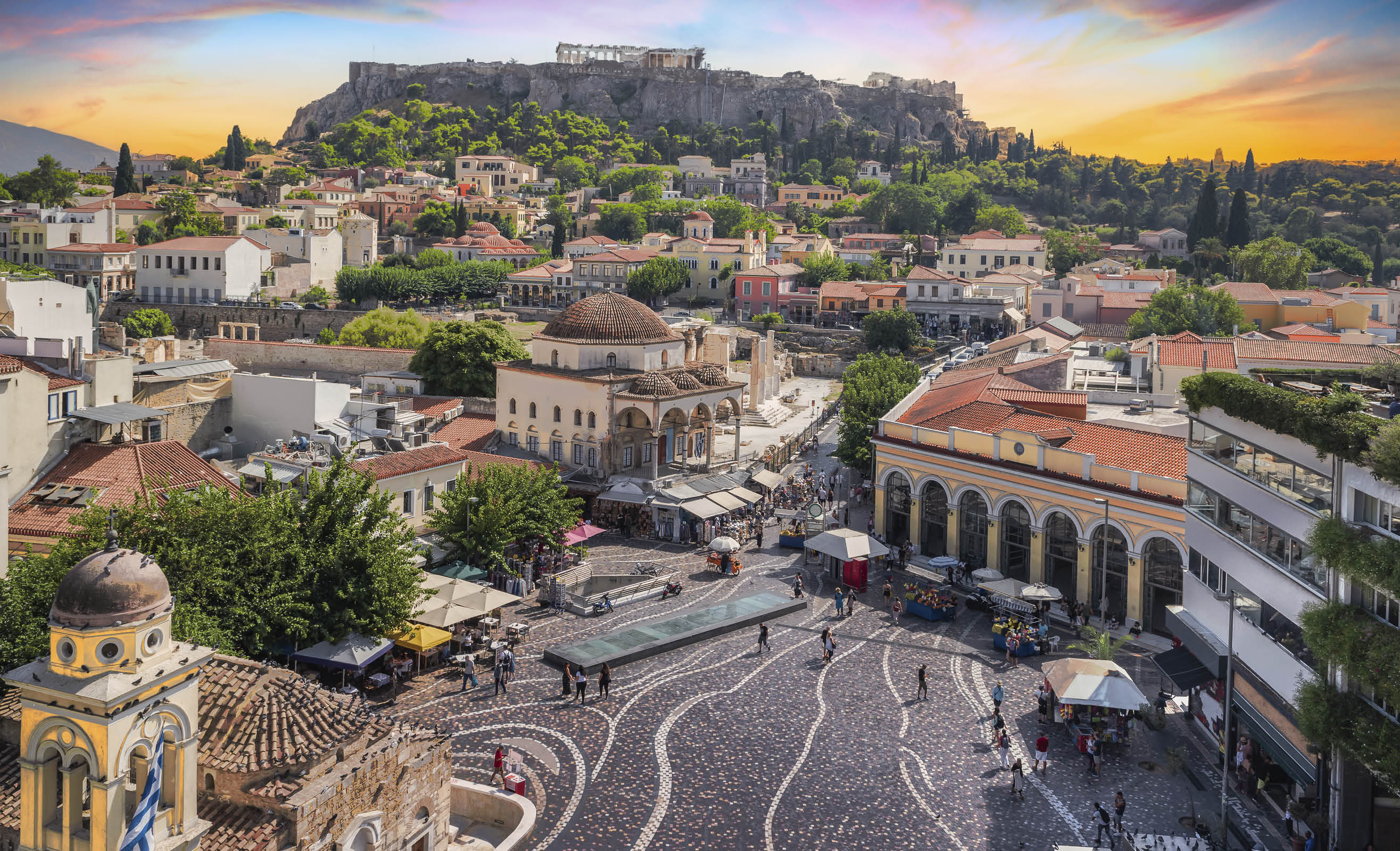 Aerial view of popular Monastiraki square with the church of Pantanassa and the city view with the Acropolis site and Parthenon on the hill on a beautiful day with fascinating sky during sunset. Popular travel destination in Europe.